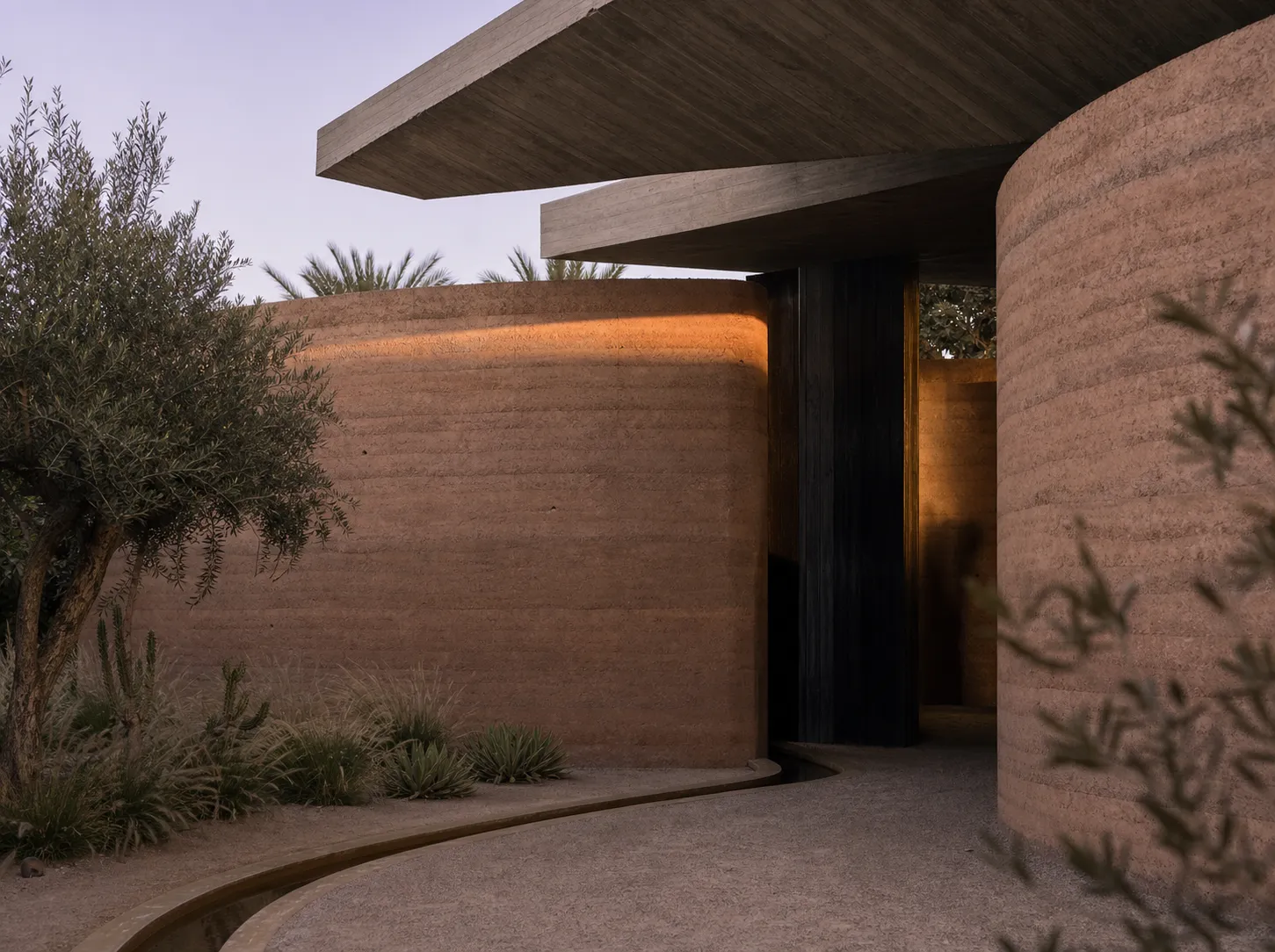 Villa Sōma, villa contemporaine en pisé aux murs courbes sous toiture de béton flottante dans la Palmeraie à Marrakech